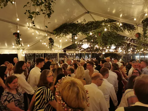 Kāzu zāle ar maigu gaismojumu, klātiem galdiem un deju grīdu